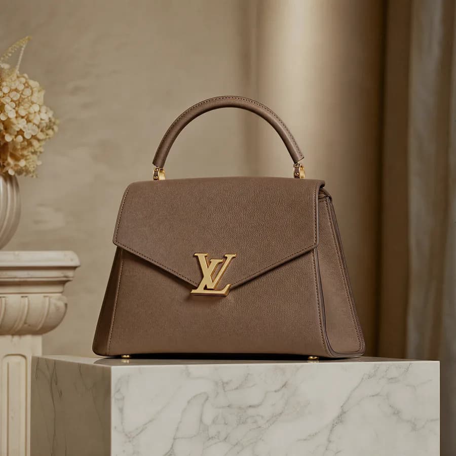Designer handbag on stone, soft studio key, editorial styling